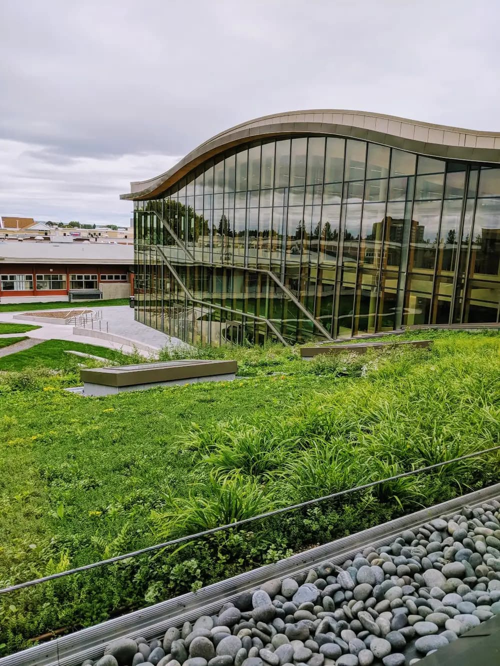Curved glass wall of the DARE District at Algonquin's Ottawa Campus, seen across a planted green roof