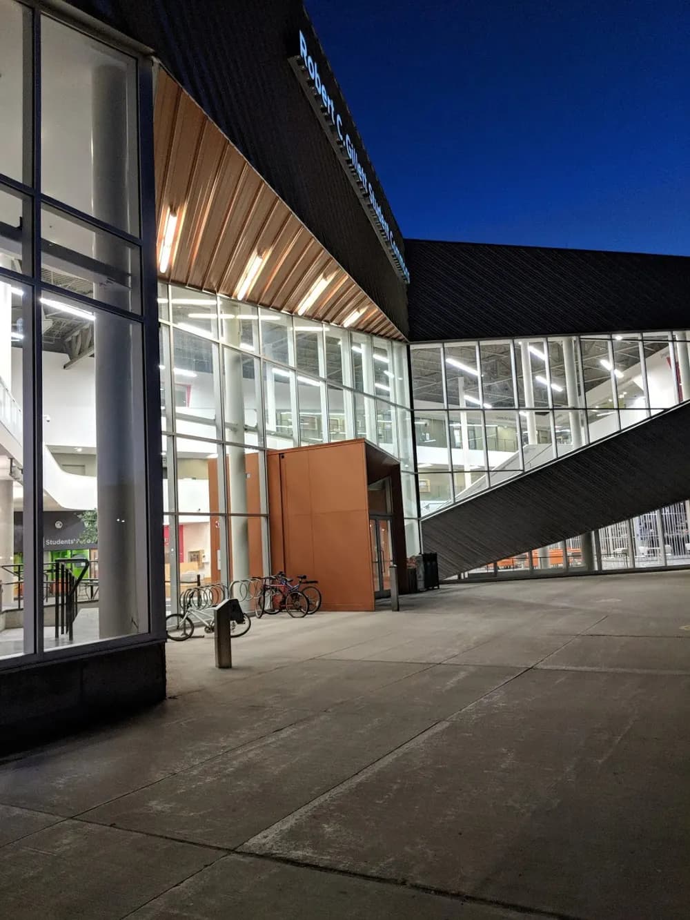 Lit glass entrance of the Robert C. Gillett Student Commons at Algonquin's Ottawa Campus at dusk