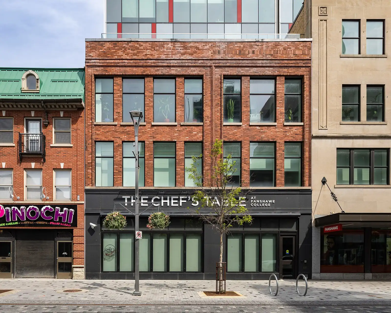 Red brick storefront on Dundas Street with a black sign reading The Chef's Table at Fanshawe College