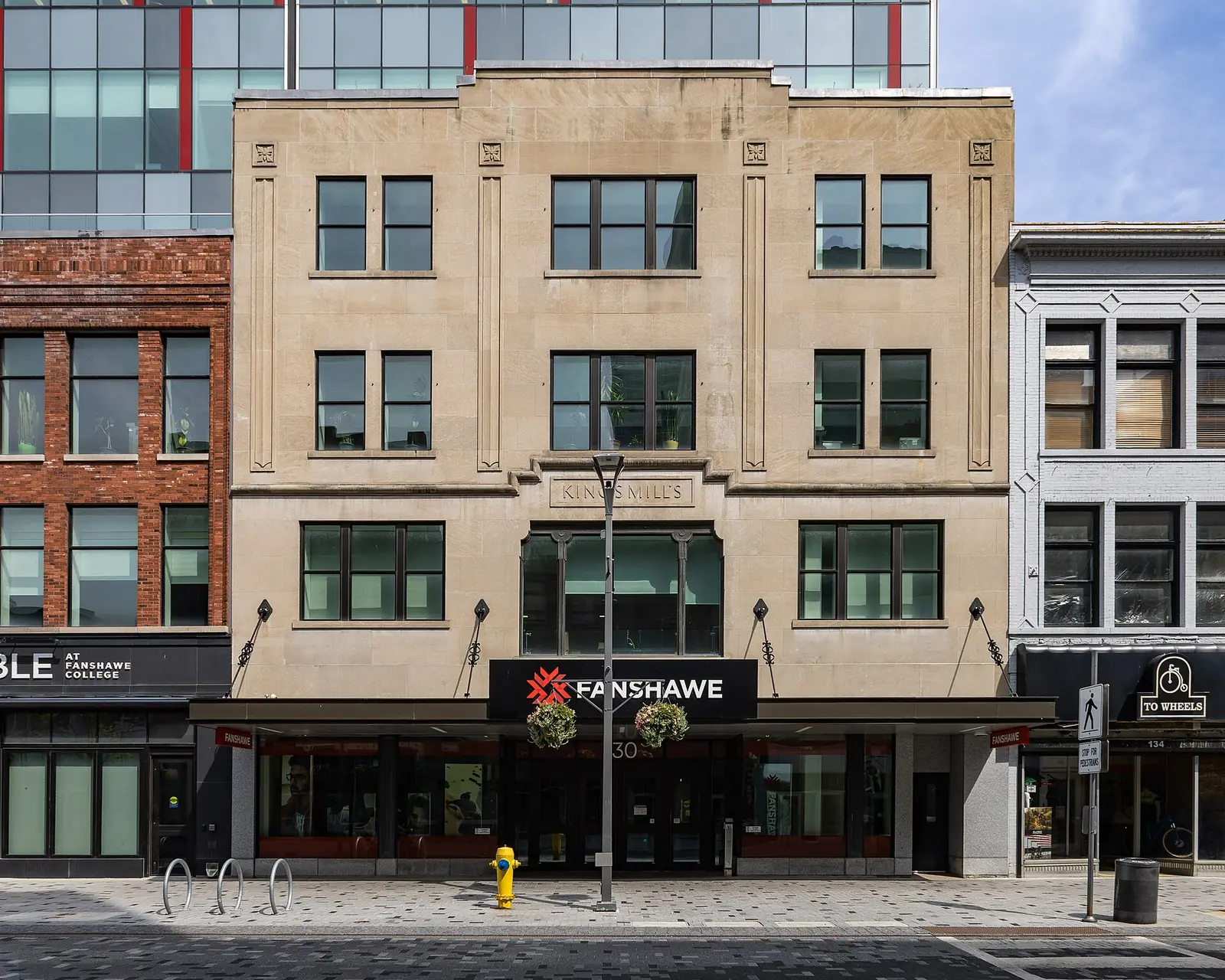 Stone front of the King's Mills building at 130 Dundas Street with a red and black Fanshawe sign over the doors