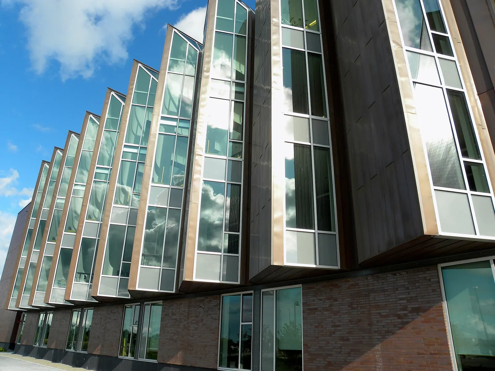 Angled glass bay windows along the brick and copper wall of the Progress Campus library building