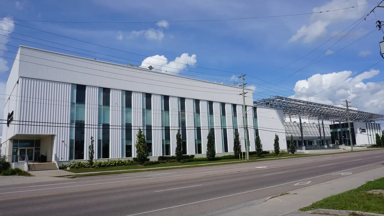 Long white ribbed building with tall windows and a steel canopy at Conestoga's Waterloo Campus