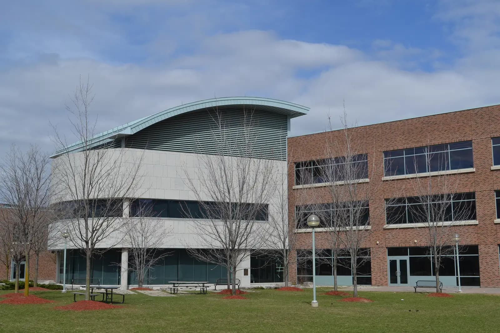 Seneca@York campus building with a curved metal roof beside a brick wing and lawn