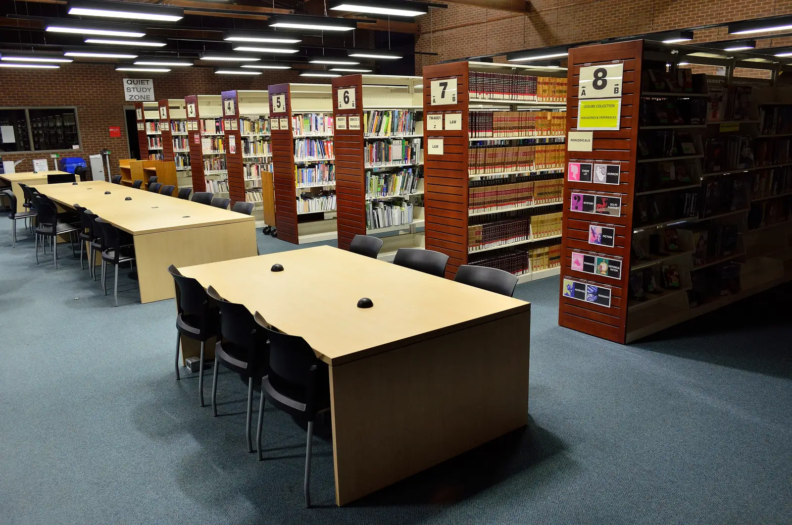 Study tables beside numbered bookshelves inside the Seneca King Campus library