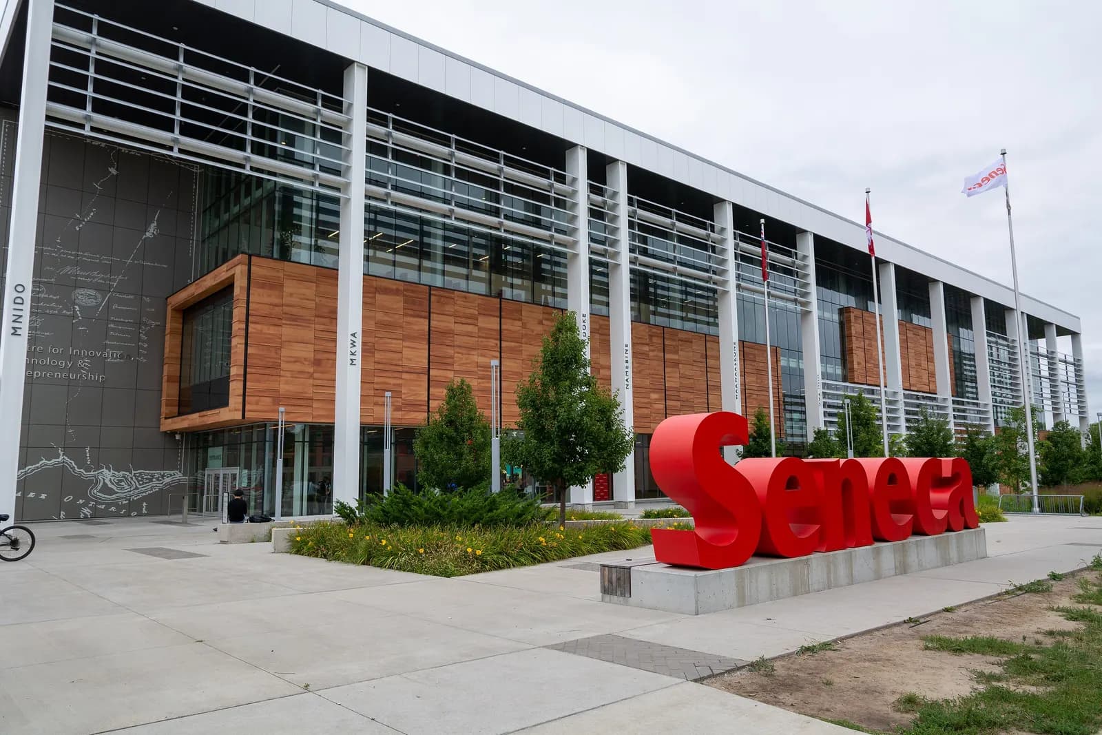 Glass and timber front of Seneca's CITE building at Newnham Campus, with a red Seneca sign