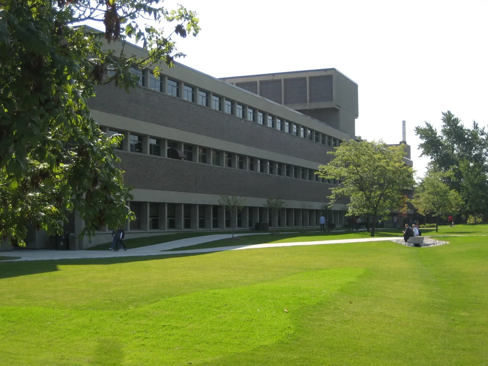 Long three-storey concrete and brick building at Mohawk's Fennell Campus seen across a wide green lawn with paths and trees