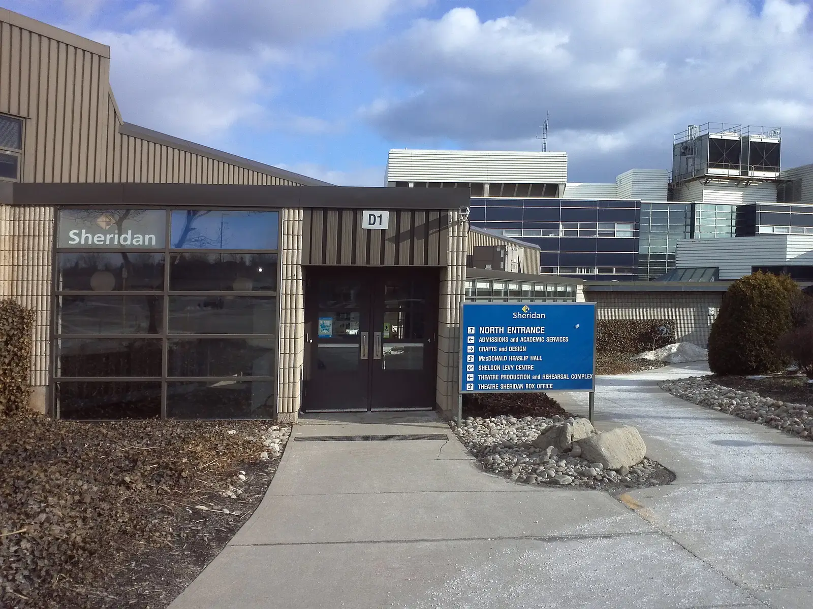 Door D1 at Sheridan's Trafalgar Campus in Oakville, with a blue North Entrance sign listing admissions and Theatre Sheridan
