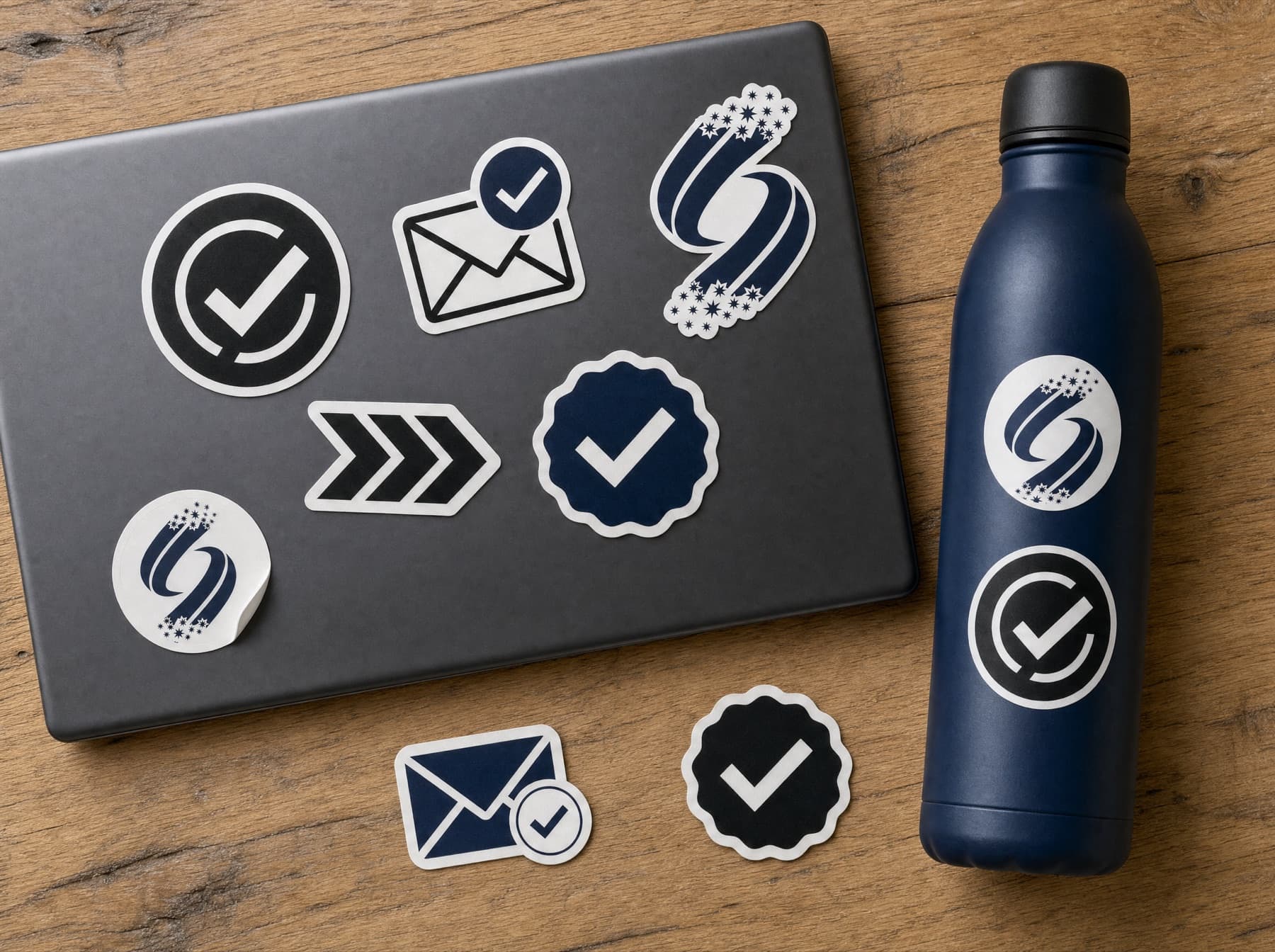 Navy, white, and black Acceptance Day stickers on a laptop and water bottle