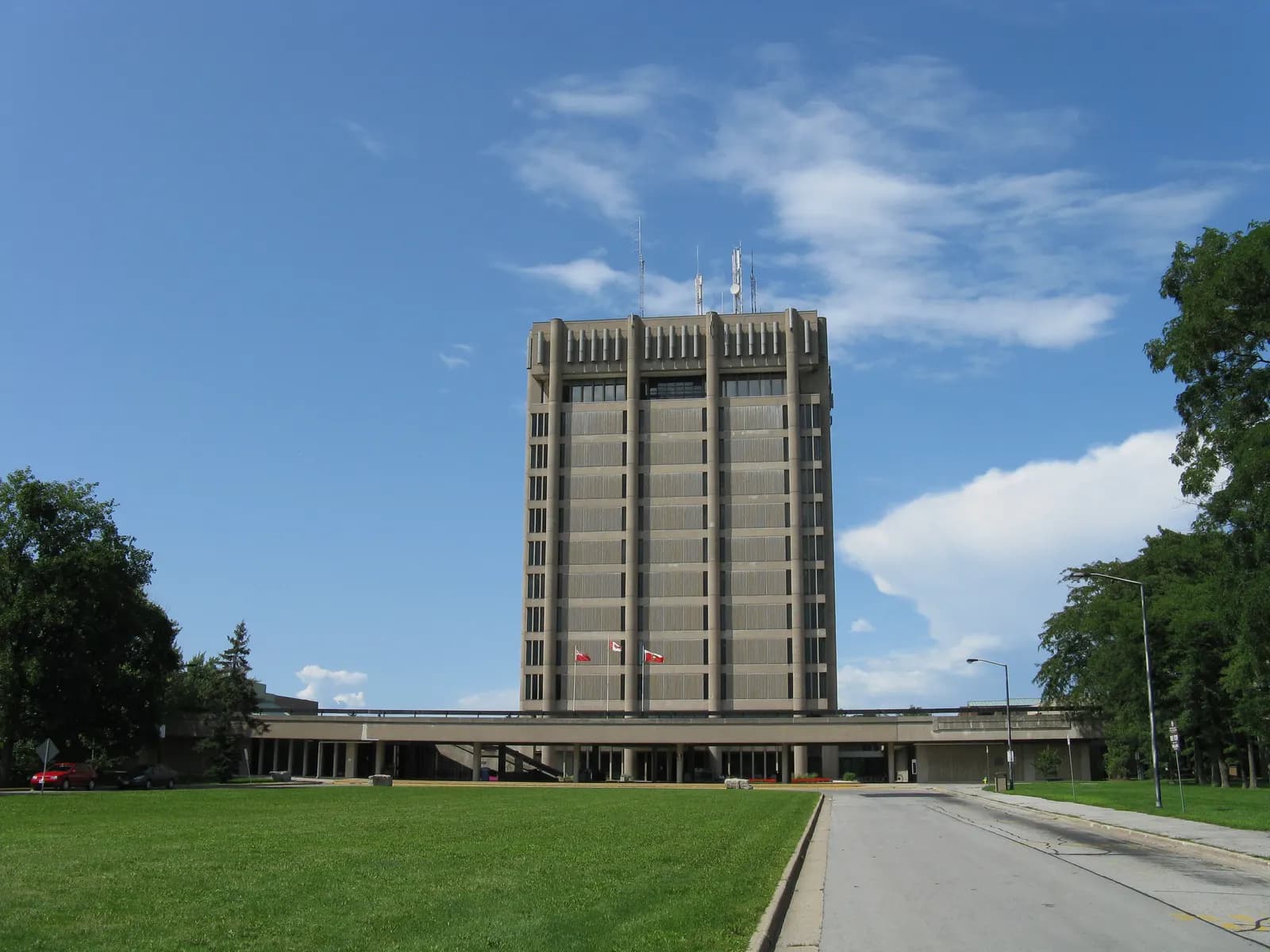 Arthur Schmon Tower, a tall concrete building at Brock University, seen across a lawn under a blue sky