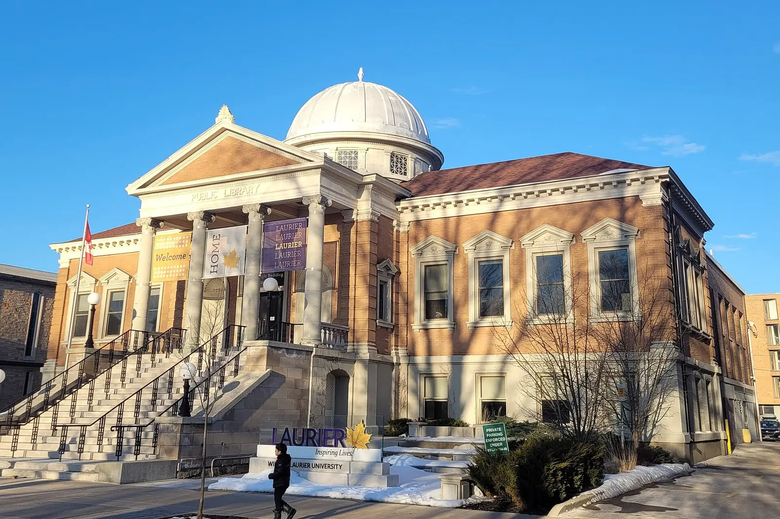 Domed Carnegie Building with columns and Laurier banners in downtown Brantford, with a Laurier sign in front