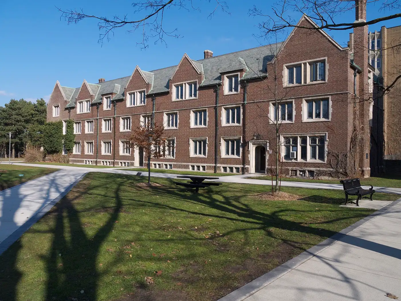 Three-storey brick exterior of Edwards Hall, a traditional McMaster residence, beside a lawn and walkway