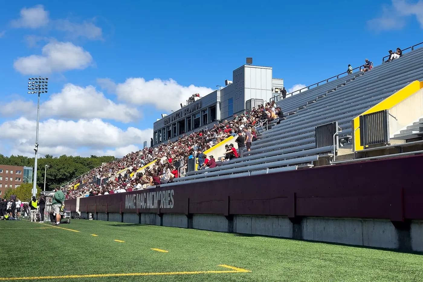 Fans in the stands at McMaster's Ron Joyce Stadium during a homecoming football game on a sunny day