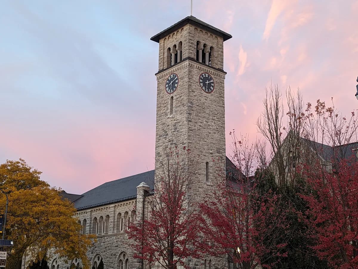Grant Hall's clock tower above autumn trees on Queen's Main Campus