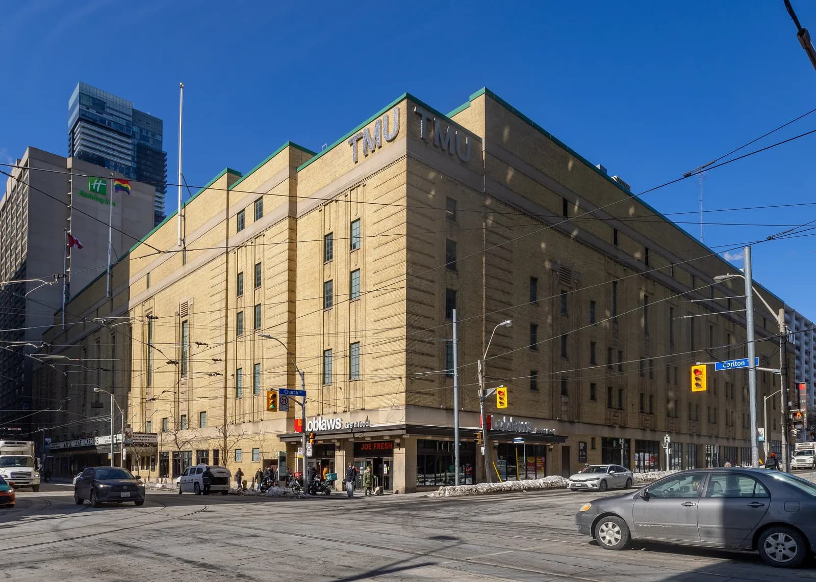 Yellow-brick former Maple Leaf Gardens at Church and Carlton streets with TMU lettering high on the corner and a Loblaws store at street level
