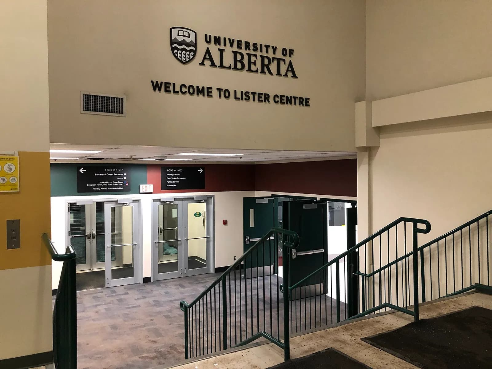 Inside the Lister Centre entrance, a sign reading Welcome to Lister Centre above glass doors, direction signs to the residence halls and a staircase with green railings