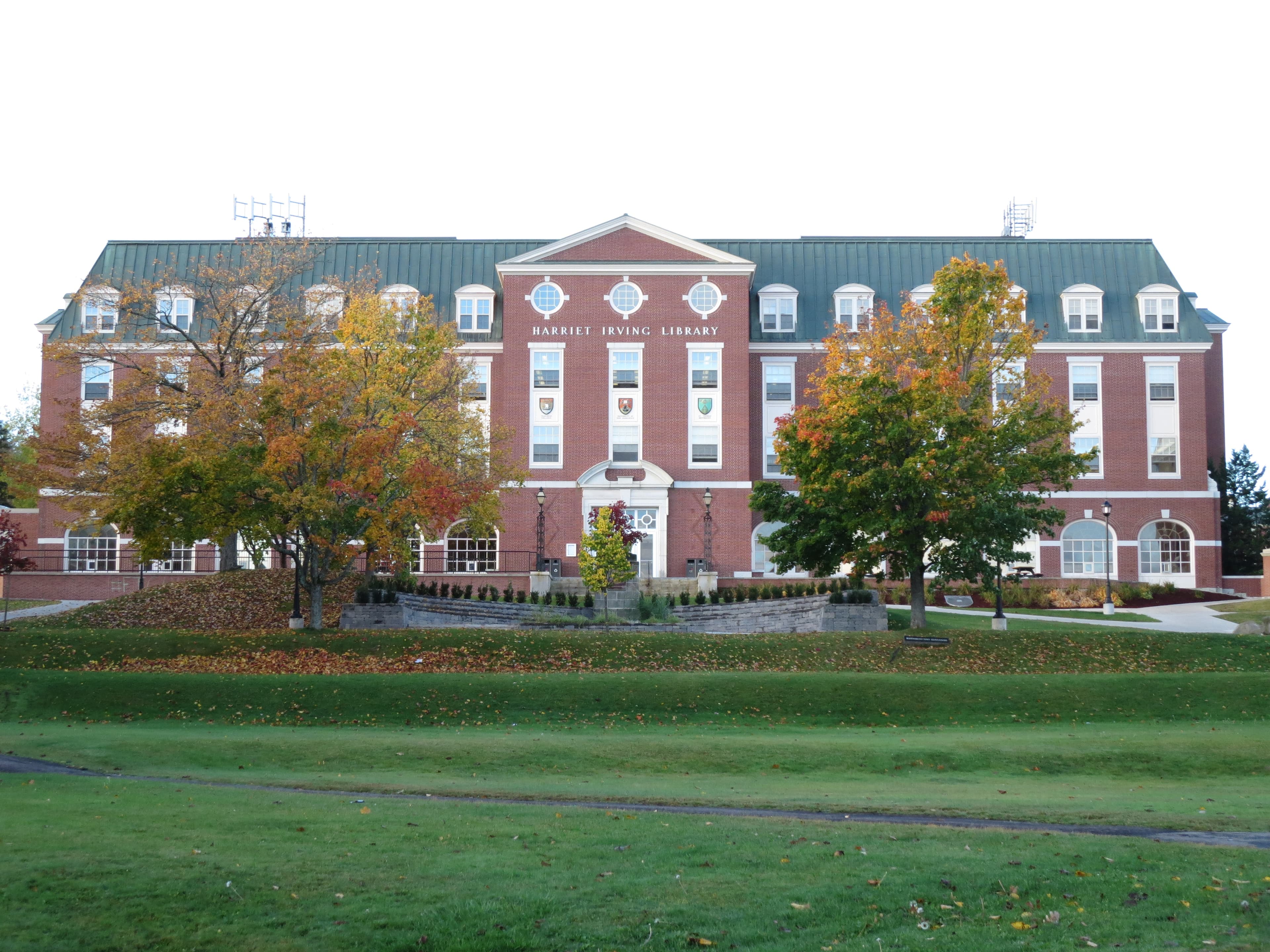 Harriet Irving Library’s brick front and entrance behind autumn trees at UNB Fredericton