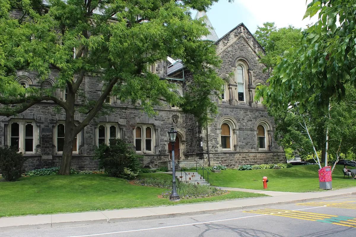 Grey stone Gerstein Science Information Centre with arched windows behind a large tree and a lawn