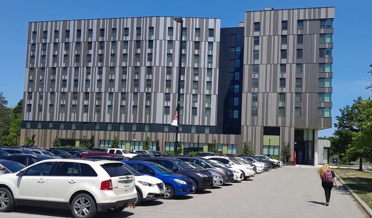 Harmony Commons residence at U of T Scarborough, with its metal facade and entrance beside a parking area