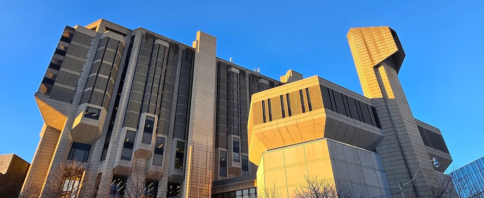 Concrete towers of Robarts Library lit by late-afternoon sun against a clear blue sky