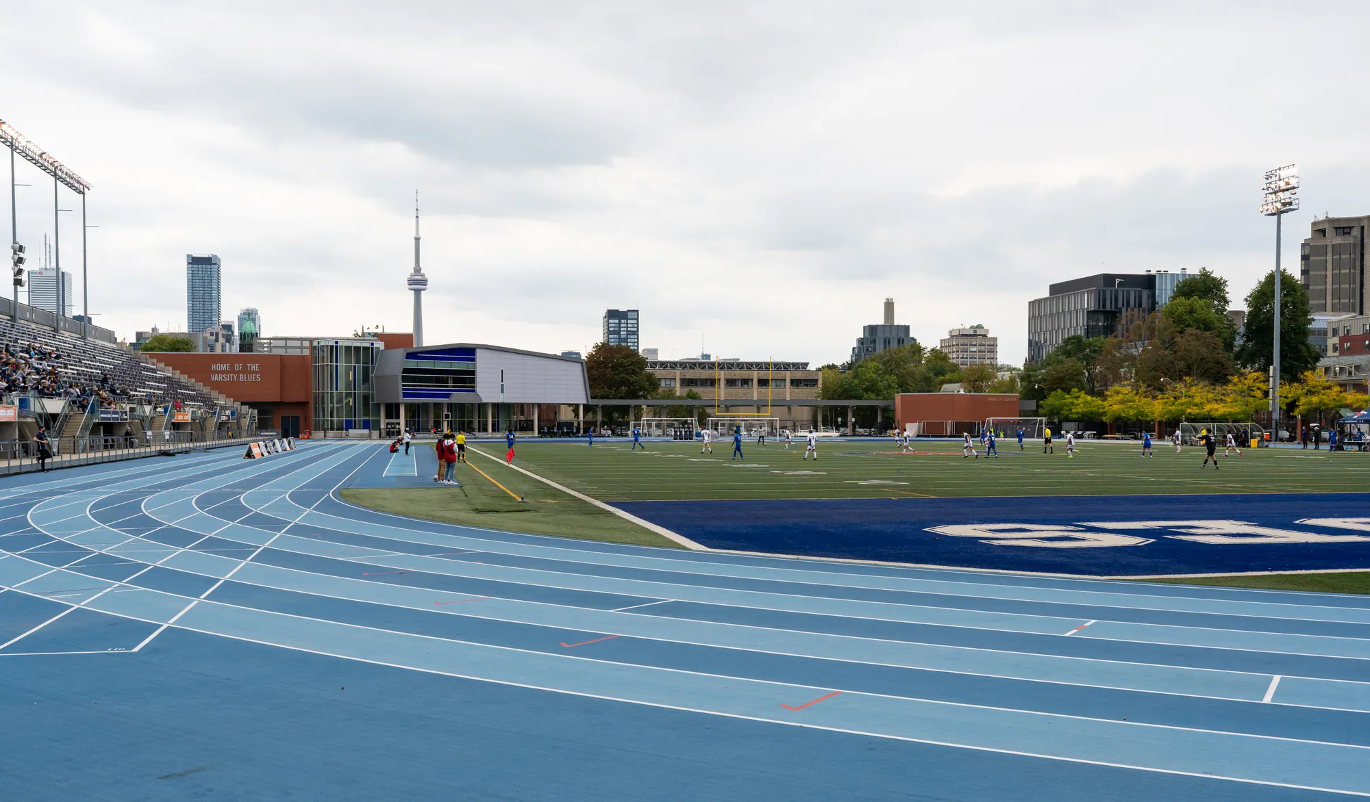Blue running track and field at Varsity Stadium with the CN Tower in the distance