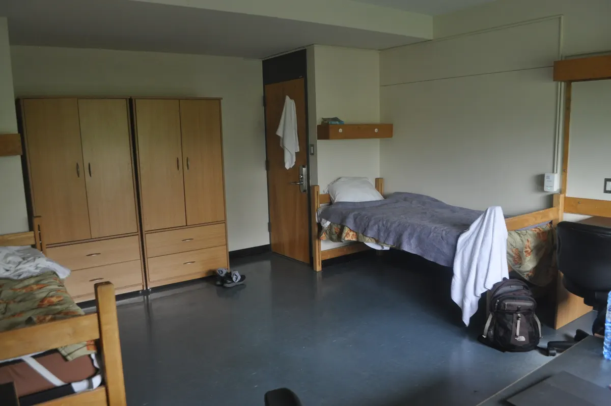 Two beds and wooden wardrobes in a Wetmore Hall room at New College