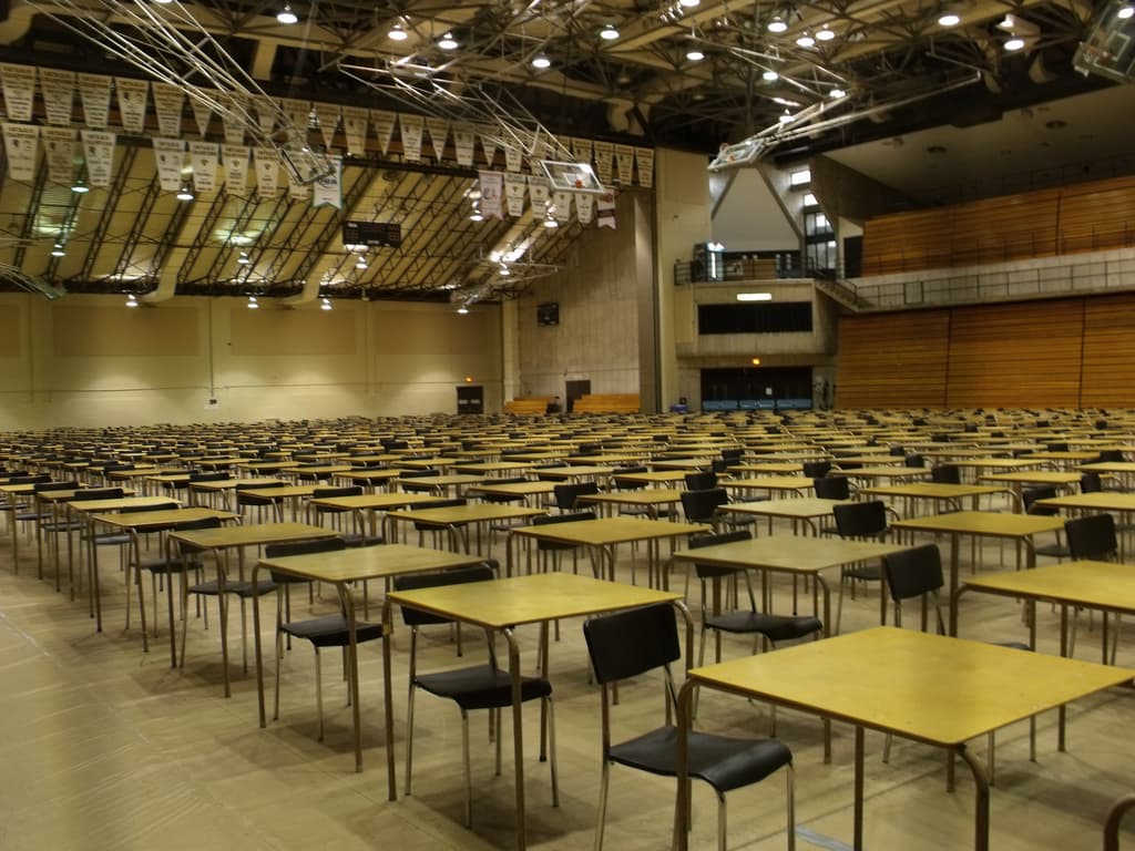 PAC gym interior with rows of exam tables, basketball hoops, wall banners and folded bleachers