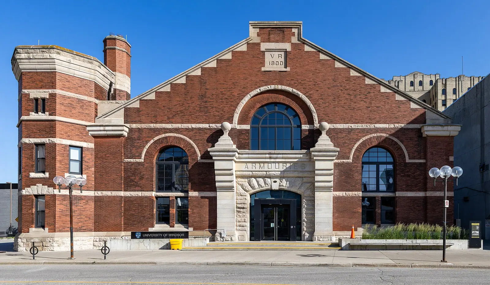 Red brick Windsor Armouries with stone trim, arched windows, an ARMOURIES entrance and a University of Windsor sign