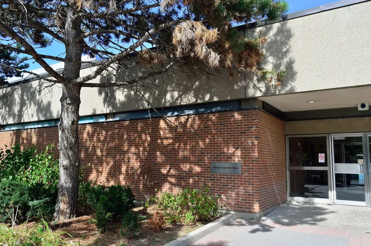 Brick entrance of the Steacie Science Library at York University behind a pine tree
