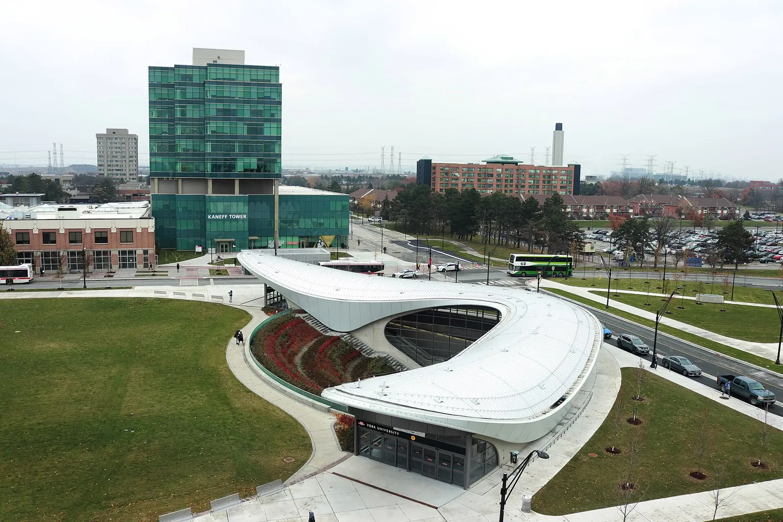 Aerial view of the curved white roof of York University subway station, with Kaneff Tower and campus roads behind